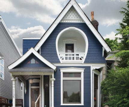 Exterior of blue home with horseshoe shaped balcony.