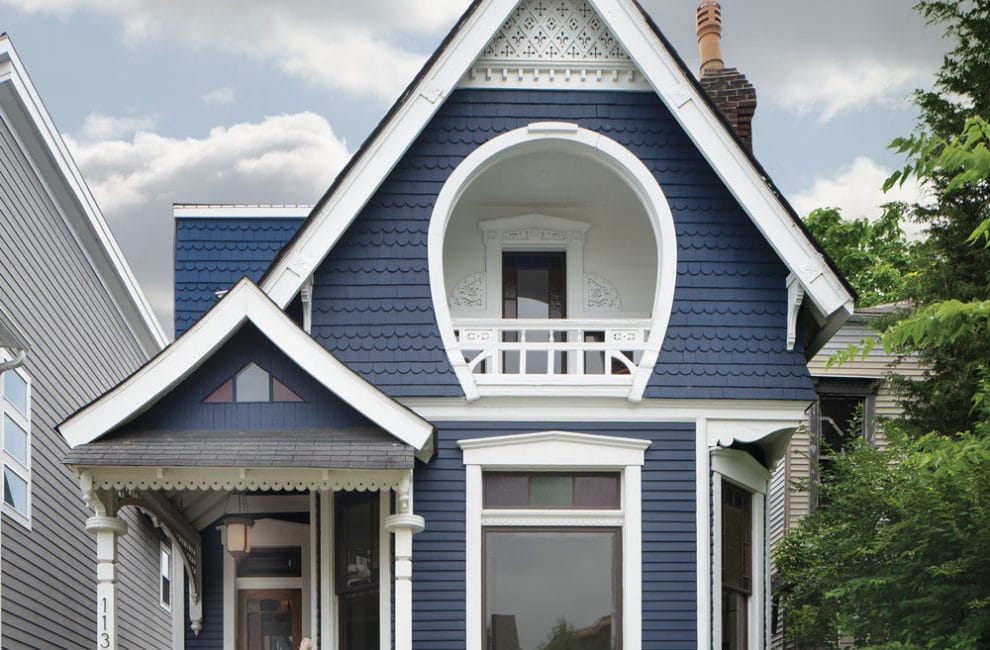 Exterior of blue home with horseshoe shaped balcony.