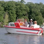 A candy-colored boat with tailfins cruises the Kalamazoo River.