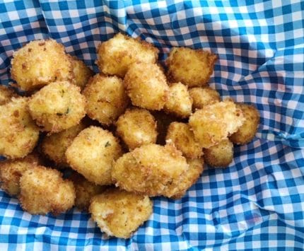 Breaded cheese curds piled on blue checked paper