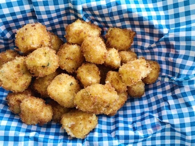 Breaded cheese curds piled on blue checked paper