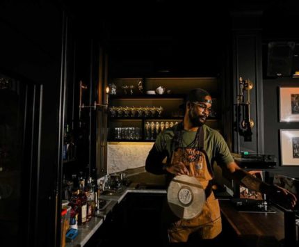 Manager and cocktail director Daimien Weems holds a vinyl album behind the bar.