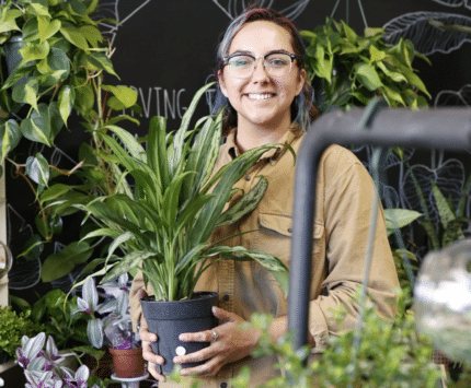 A woman holding a plant in a shop