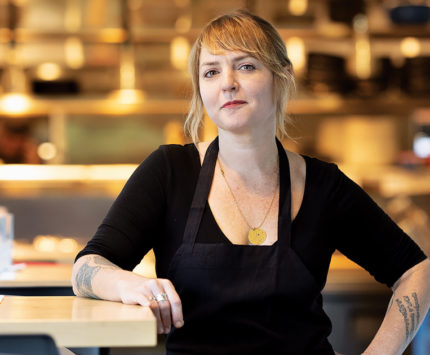 Woman in black leaning against a counter