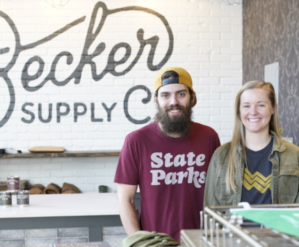 A man and woman smiling inside their shop