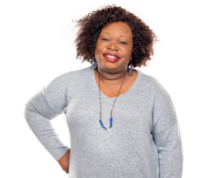 A smiling woman wearing a gray sweater