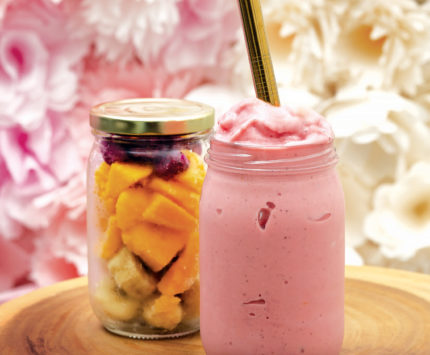 A glass jar of fresh fruit and a glass jar containing a pink smoothie