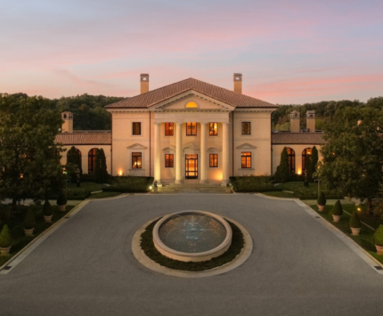 A white mansion at twilight with a fountain