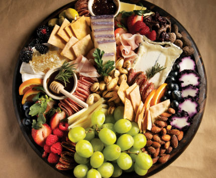 a charcuterie board of sliced meats, cheeses, and fruit