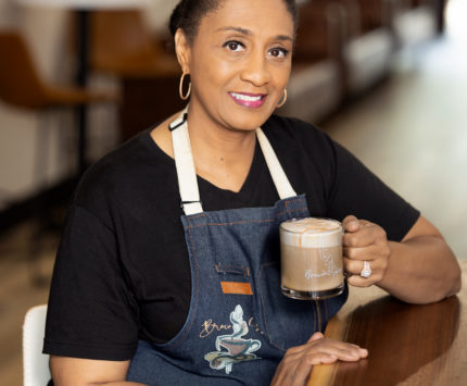 A woman holding a glass mug of coffee