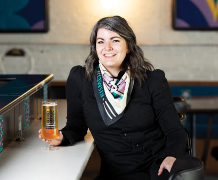 Nicole Oesch smiling holding a beer