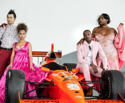 Models posing on an IndyCar for Indiana Fashion Week
