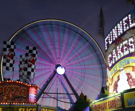 New Foods at The State Fair Midway image of ferris wheel and food vendors at twilight