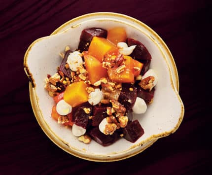 A bowl of golden and red beets with dollops of white cheese