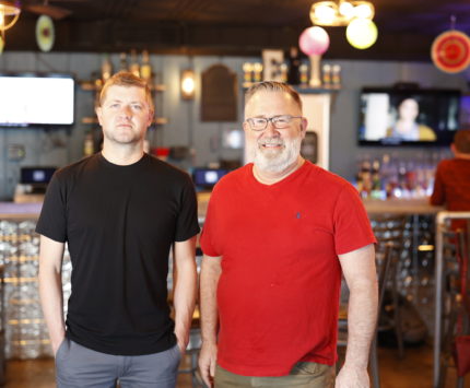 two men standing in a bar