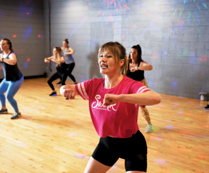 A woman dancing in a red Swerk t-shirt with a group of other women