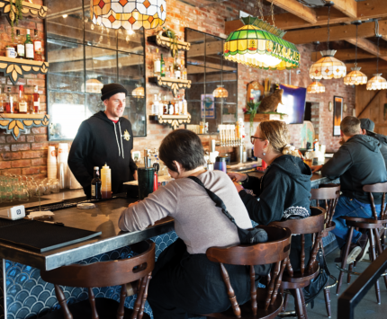The bartender chats with patrons at the bar of Natural State