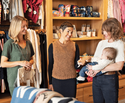 Three women in a child's store looking at a baby